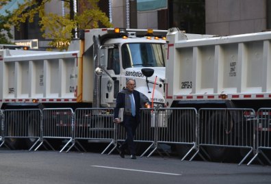 A man walks near a protective barrier of Sanitation Department trucks parked in front of Trump Tower on 5th Avenue to provide security to US President-elect Donald Trump on November 10, 2016 in New York. / AFP / TIMOTHY A. CLARY (Photo credit should read TIMOTHY A. CLARY/AFP/Getty Images)